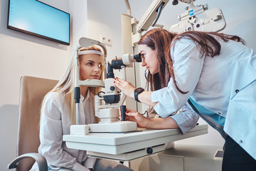 Two attractive females in oculist cabinet, one of them is a doctor, the second one is a patient.