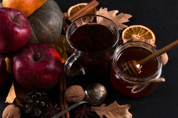 Obraz na płótnie Canvas Tea, may liquid honey, fruits, cinnamon, dried oranges and nuts on a black background. autumn harvest, copy space.