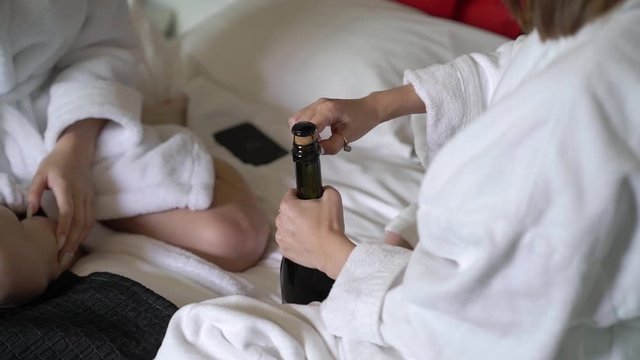 Girls opening bottle of champagne and pour in glasses at home. Alcohol drinks and beverage