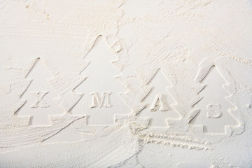 Contours of decorative Christmas trees and letters on flour. Christmas white texture background.