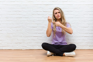 young blonde pretty woman looking impatient and angry, pointing at watch, asking for punctuality,...