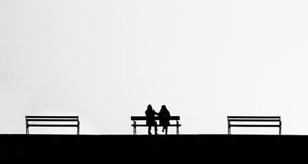 Silhouette of to people on a bench 
