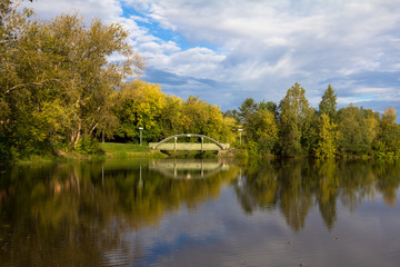 Fototapeta na wymiar view of the bridge over the pond in the park in autumn