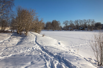 Fototapeta na wymiar the path passes through the snowdrifts along the frozen lake