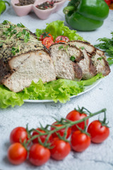 Baked pork chopped in a sauce of walnuts and mint on a white plate with fresh herbs and vegetables. Light background.