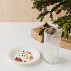 Empty glass of milk and crumb biscuits and a gift under the Christmas tree. The concept of the arrival of Santa Claus.