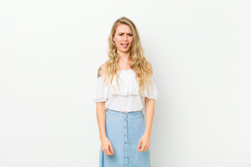 young blonde woman feeling disgusted and irritated, sticking tongue out, disliking something nasty...