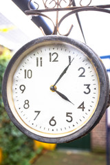 Antique vintage style clock hanging outside, hanging on the wall of a house