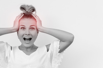 Headache. Funny attractive girl is surprised by something, touching her head with two hands with open mouth looking at the camera. Woman portrait isolated on white background.