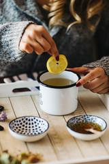 Pouring tea into a cup. Autumn hot herbal tea with honey, cinnamon and lemon. Top view. Image toned.
