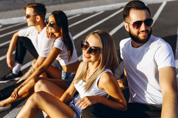 A group of young friends having fun and hanging out sitting in the city on the asphalt