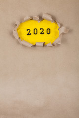 The concept of the New Year with the number 2020 placed in a leaky paper on crumpled yellow paper