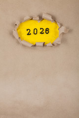 The concept of the New Year with the number 2026 placed in a leaky paper on crumpled yellow paper