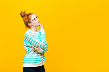 young red head woman feeling thoughtful, wondering or imagining ideas, daydreaming and looking up...