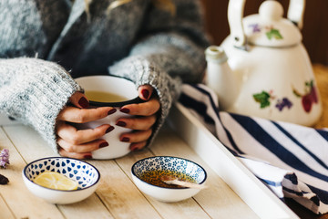 A female model is drinking herbal tea for flu, she is pouring herbal tea into a white enamel cup