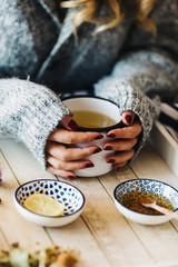 A female model is drinking herbal tea for flu, she is pouring herbal tea into a white enamel cup