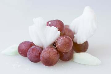 Fruits with high sugar content concept. Bunch of blue grapes and large white and light green sugar cubes in-between on white background
