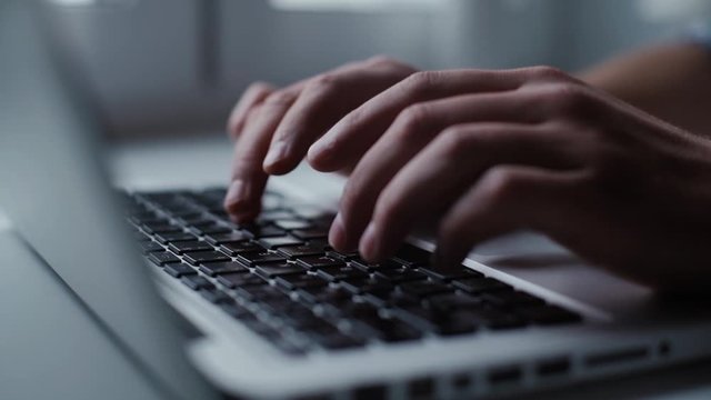 Mens hands are typing on the laptop keyboard, close-up. an enters password. Closeup man arms carefully writing on laptop computer keyboard. Shooting in slow motion
