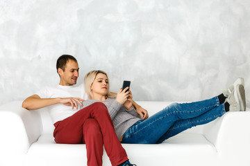 man and woman are talking on a white sofa