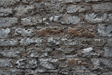 Fragment of an old stone wall of the house. Tallinn Estonia. The stones are aged from time and weather. The cementitious binder solution has recently been updated. Texture. Background.