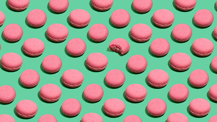 Colorful macaroni seamless pattern. Pink cookies over mint background