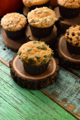 Homemade healthy pastry concept. Pumpkin muffins with seeds and chocolate close up on wood slabs on shabby green wooden background copy space