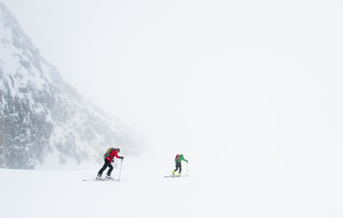 Two skiers skiing into a storm and whiteout - 300443932