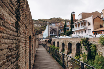 Fototapeta na wymiar 01.06.2019 Tbilisi, Georgia: view of old stone houses with beautiful colored roofs in the center of the old town where tourists are walking
