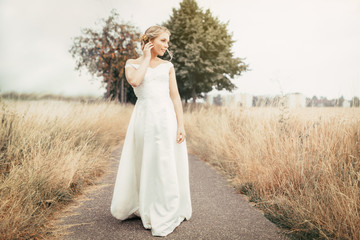 Fototapeta na wymiar blonde wedding bride in white dress outside on field
