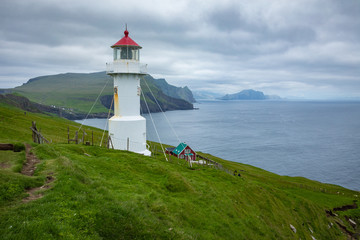 Fototapeta na wymiar Mykines lighthouse and cliffs on Faroe islands. Hiking landmark. Denmark