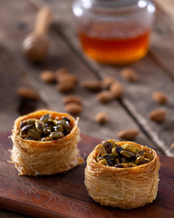 arabic sweets, nuts and honey pot in a wood table