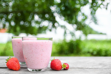 A glass of fresh cold smoothie with berries and cherrys on a wooden table, summer set, outdoor greed blured background,boke.