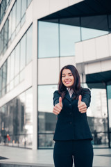 Successful smile businesswoman or entrepreneur shows thumbs up standing in front of his office.