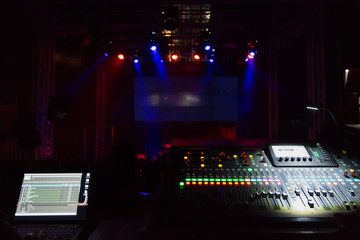 Audio sound mixer console with buttons and sliders against the concert scene.