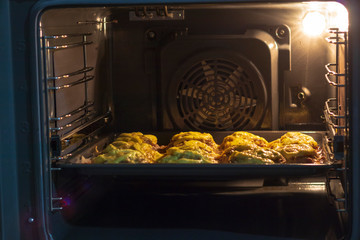 Cooking meat in the oven at home. The door is open. the horizon is littered.