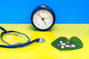 Alarm clock for the timely adoption of pills, a stethoscope, multi-colored pills, on a blue...