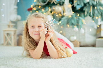 girl 5 years old with sweet lollipop candy cane near christmas tree.