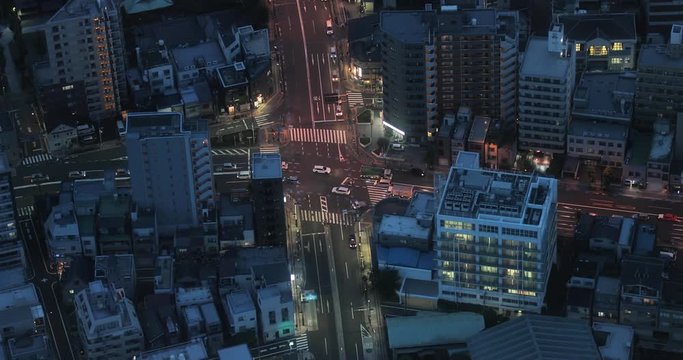 Urban city road intersection traffic with passing cars at night, aerial view. Tokyo, Japan