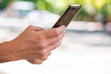 older woman hands holding cellphone outside