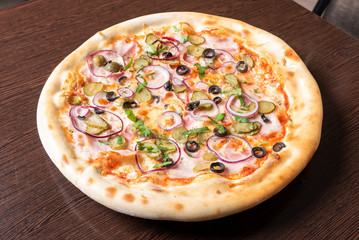 Cheap pizza with ham, onion, pickled cucumbers and olives.