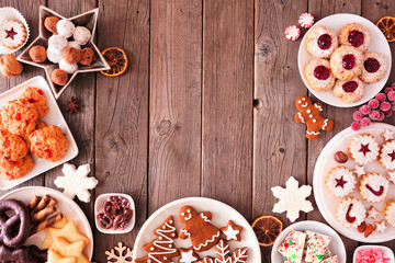 Variety of Christmas sweets and cookies. Top view arched border over a rustic wood background. Holiday baking concept.
