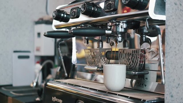 Fresh Black Coffee Pouring from Professional Machine Dispenser in Cup. 4K, Macro Slowmotion.