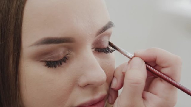 Professional makeup artist woman stirs makeup cream on a palette.