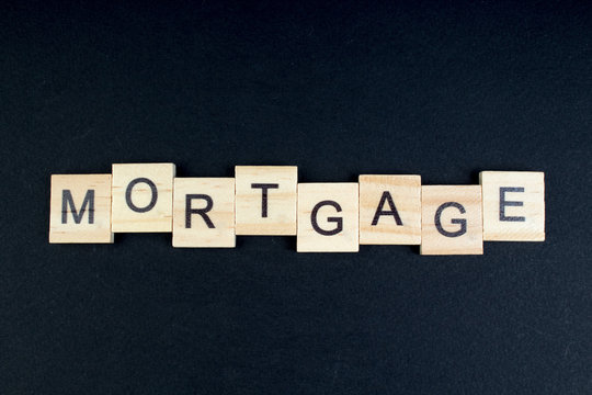mortgage- word composed fromwooden blocks letters on black background, copy space for ad text.