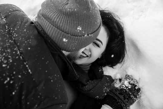 Black and white phoro of beautiful girl, she fooling around with her beloved boyfriend in the snow. Amazing girl with charming smile