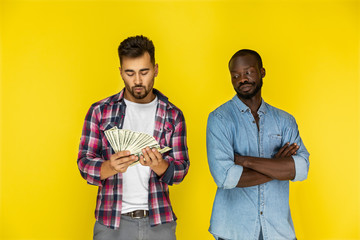 european guy is counting money and afroamerican guy is humiliating looking at him