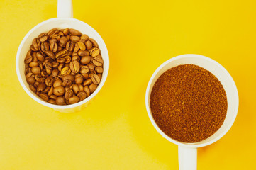 Coffee beans and ground coffee in cups on yellow background