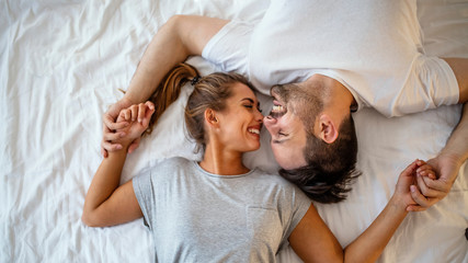 Guy and a girl in a cozy home environment. Happy man and woman lying in the bedroom stock photo....