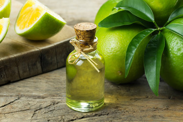 Glass bottle of lemon essential oil and fresh green lemons on wooden rustic background, alternative medicine aromatherapy and Spa concept