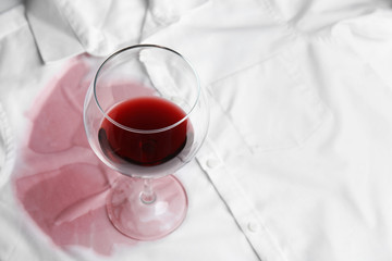 Transparent glass and spilled exquisite red wine on white shirt. Space for text